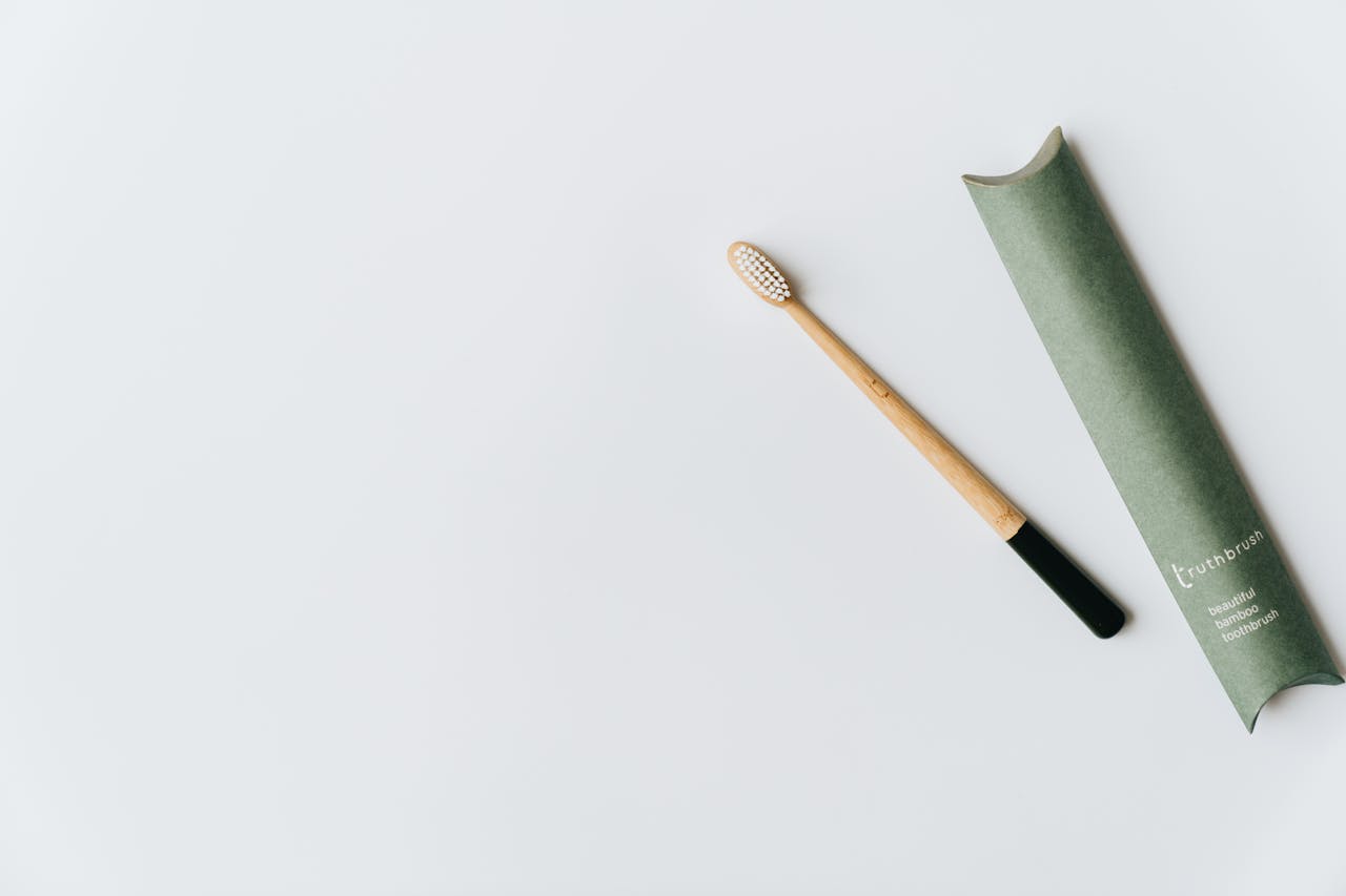 hero-img-02 Minimalist bamboo toothbrush with green eco-friendly packaging on white background.
