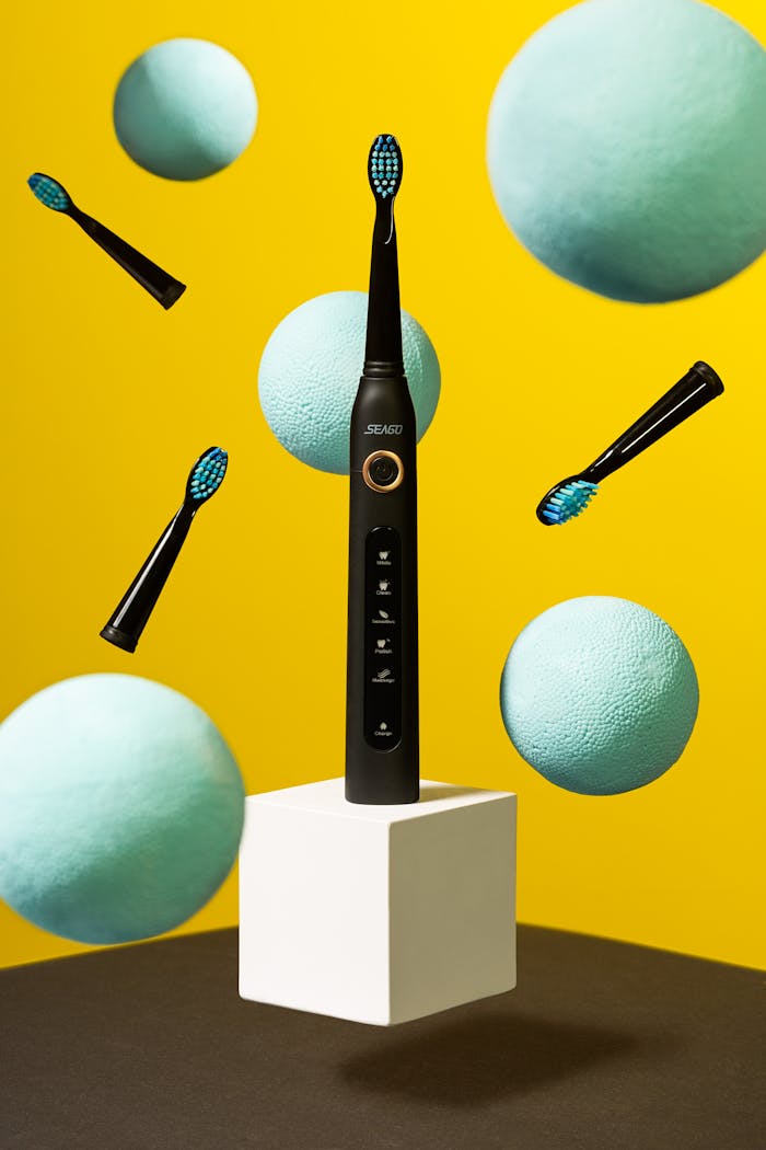 hero-img-01 Dynamic studio shot of an electric toothbrush with colorful floating elements.